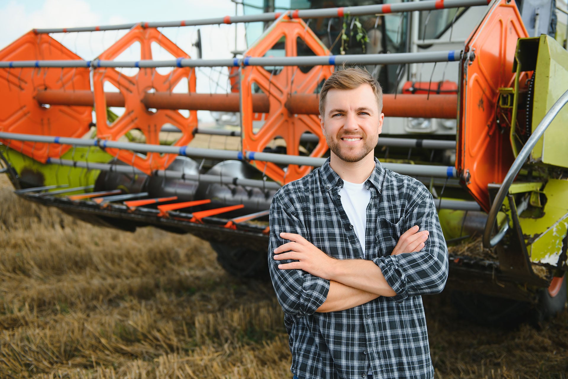 Farmer standing beside agricultural harvesting equipment