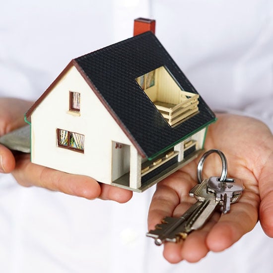Hands holding house keys and a model home